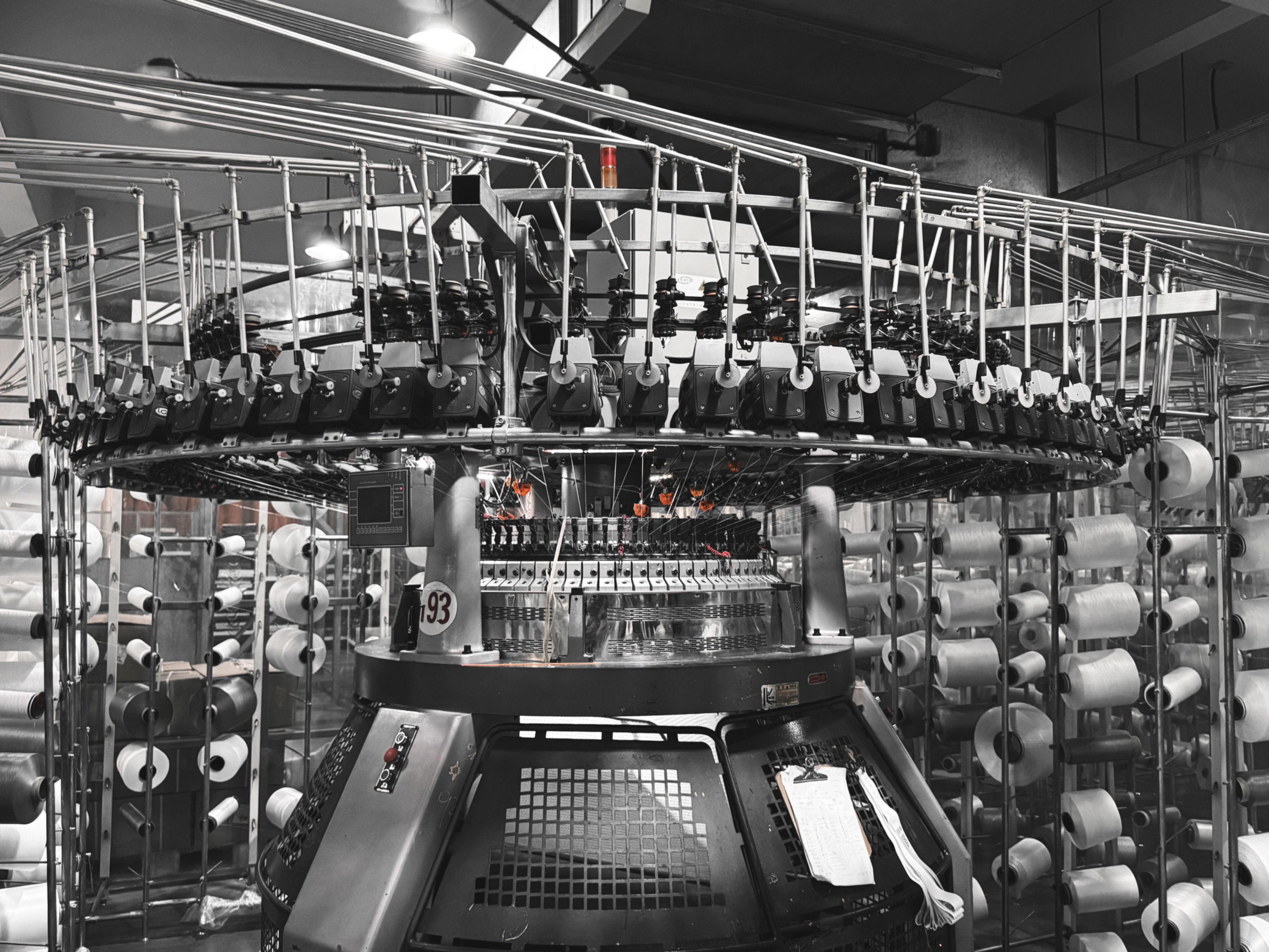 面料工厂中的圆形针织设备与纱线卷 / Circular knitting machinery and yarn spools in a fabric factory
